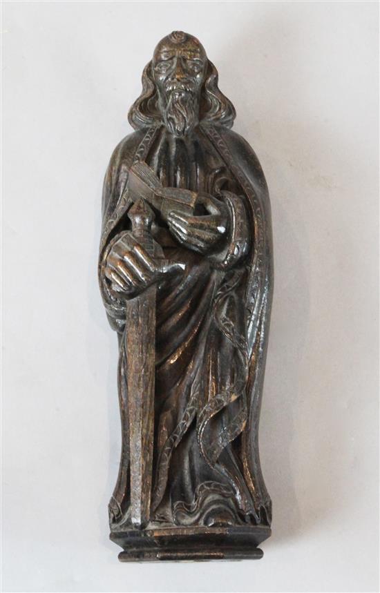 A 17th century carved oak figure of St. John the Evangelist with a sword and a book, 15in.